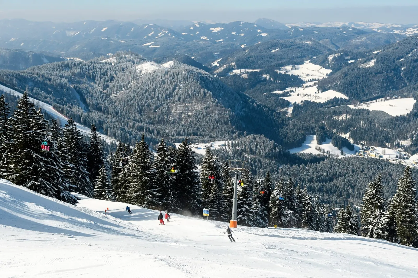 Síelők és ülőlift a havas hegyek panorámájával